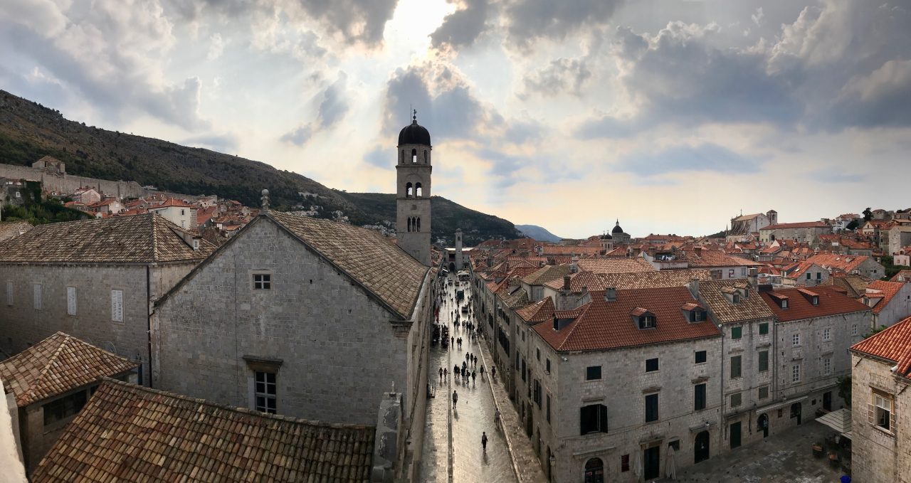 Dubrovnik Altstadt links und rechts die mittelalterlichen Häuser in der Mitte die Promenade. Am frühen Morgen sind nur wenige Menschen unterwegs, die Wolken werfen ein mystisches Bild auf die Altstadt