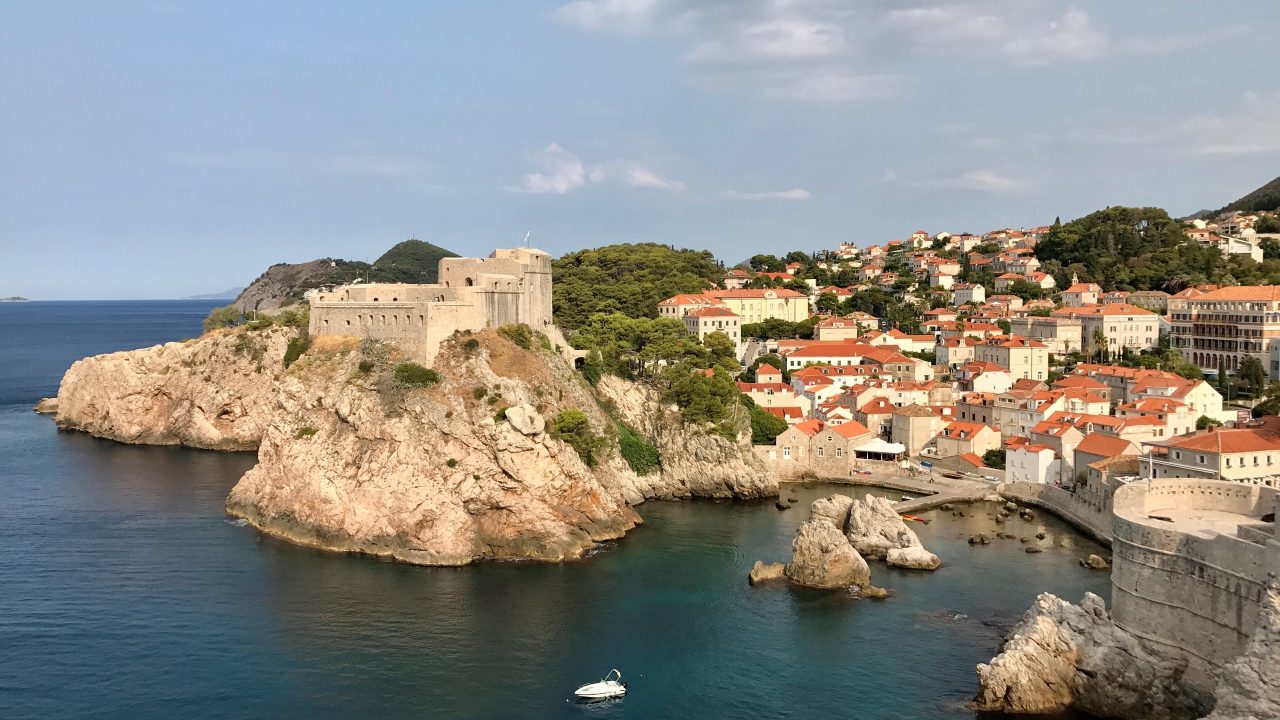 Blick von der Dubrovnik Stadtmauer auf die Festung Festung Lovrijenac. Ein sonnenbestrahlter Fels und drumherum das Meer