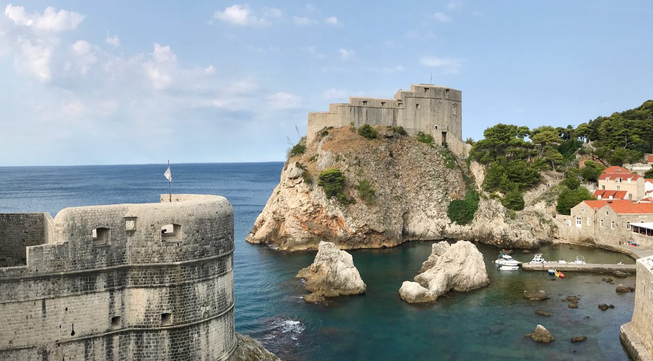 Blick von der Dubrovnik Stadtmauer auf die Festung Festung Lovrijenac. Ein sonnenbestrahlter Fels und drumherum das Meer