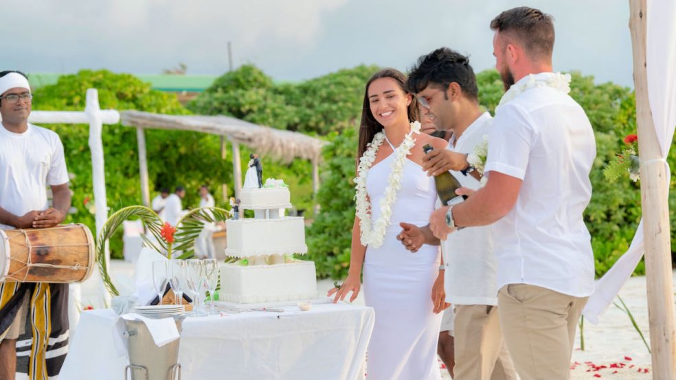 Malediven Reise You & Me by Cocoon Hochzeitspaar am Strand mit Hochzeitstorte